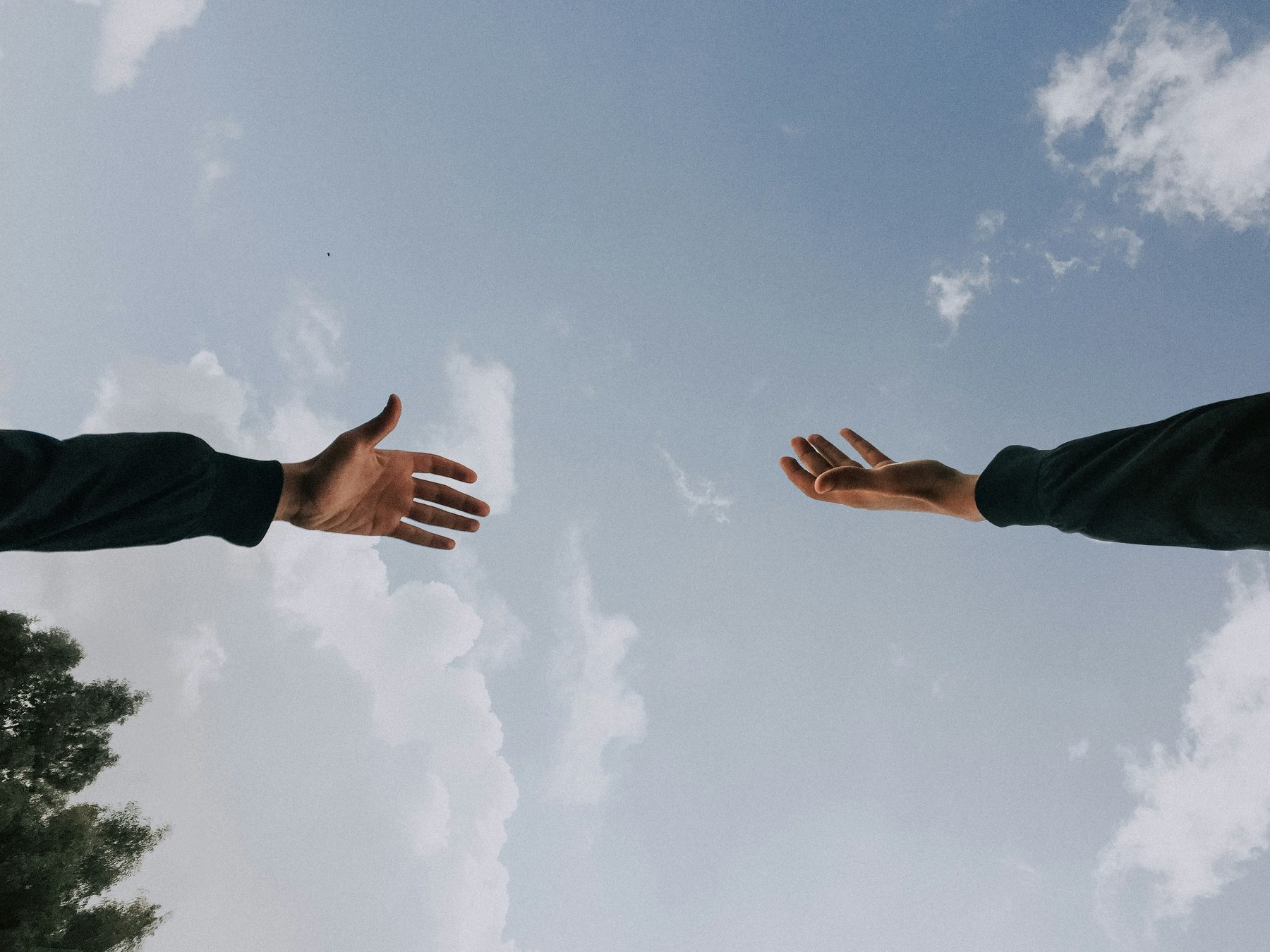 Two hands reaching toward each other across the sky.